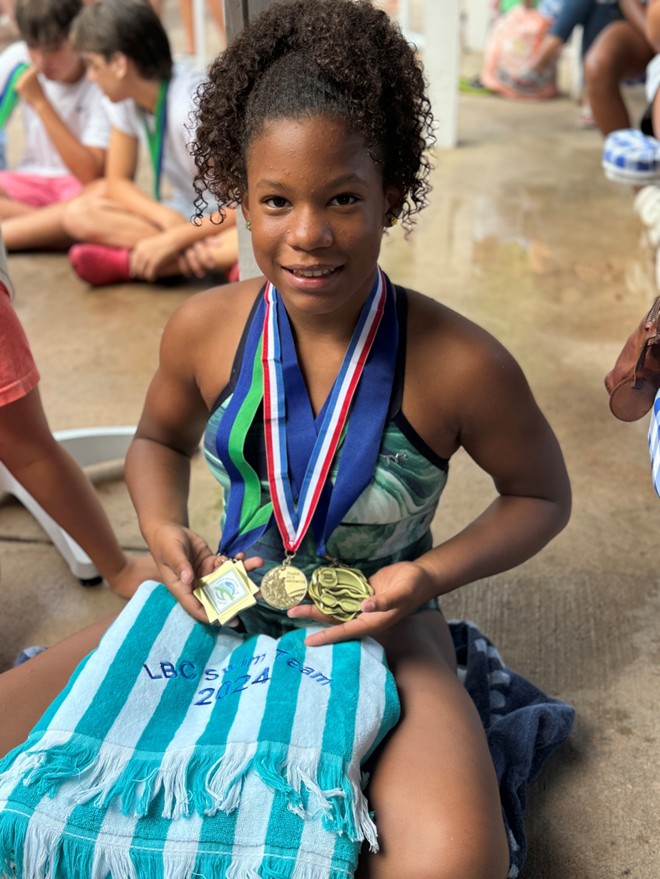Maritza as a child showcasing her medals celebrating diversity in swimming